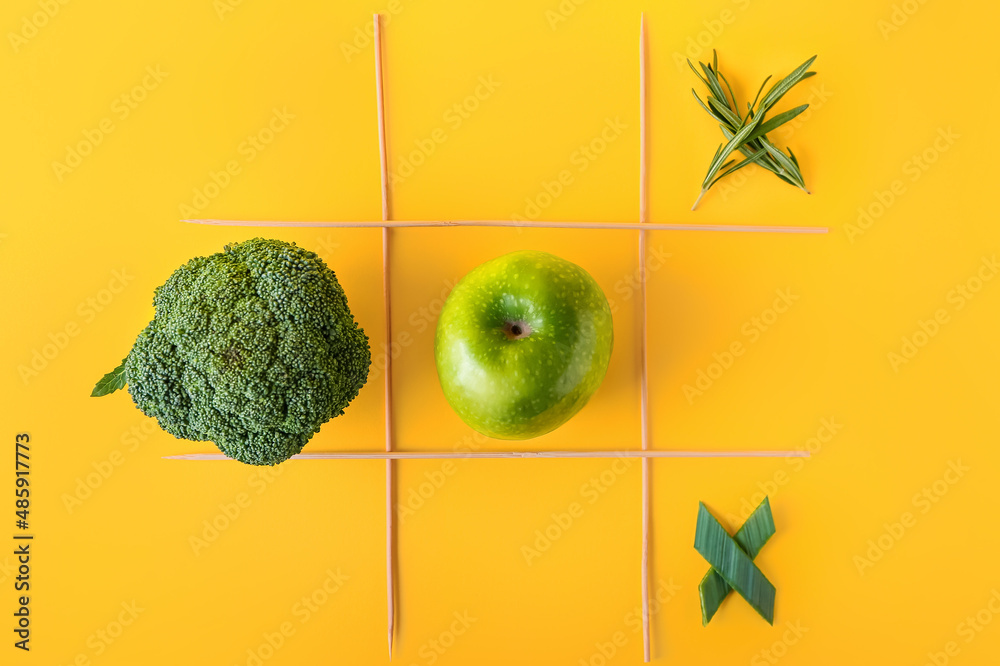 Creative composition with broccoli and apple on yellow background