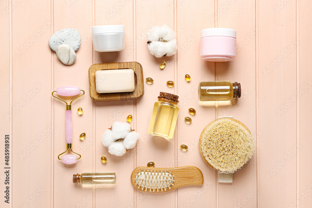 Composition with bottles of essential oil, pills and bath supplies on color wooden background