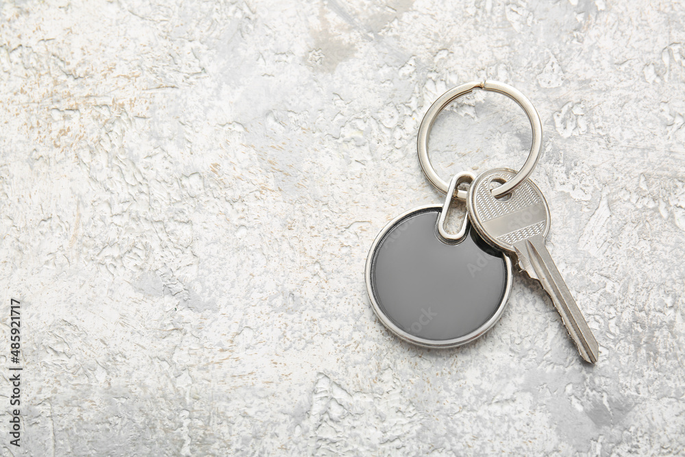 Key with stylish round keychain on light background