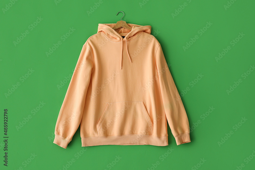 Stylish peachy hoodie on green background