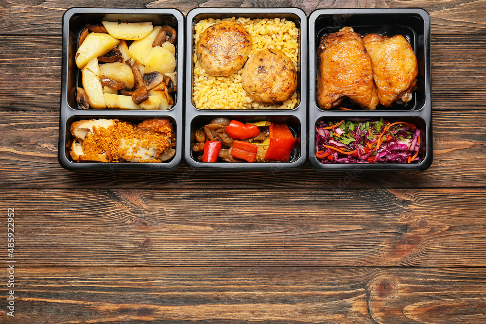 Food containers with different meals on wooden background