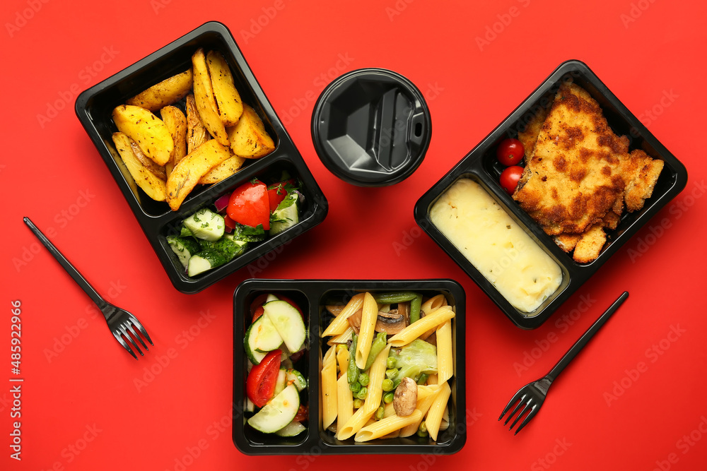 Lunch boxes with food, paper cup with drink and forks on color background