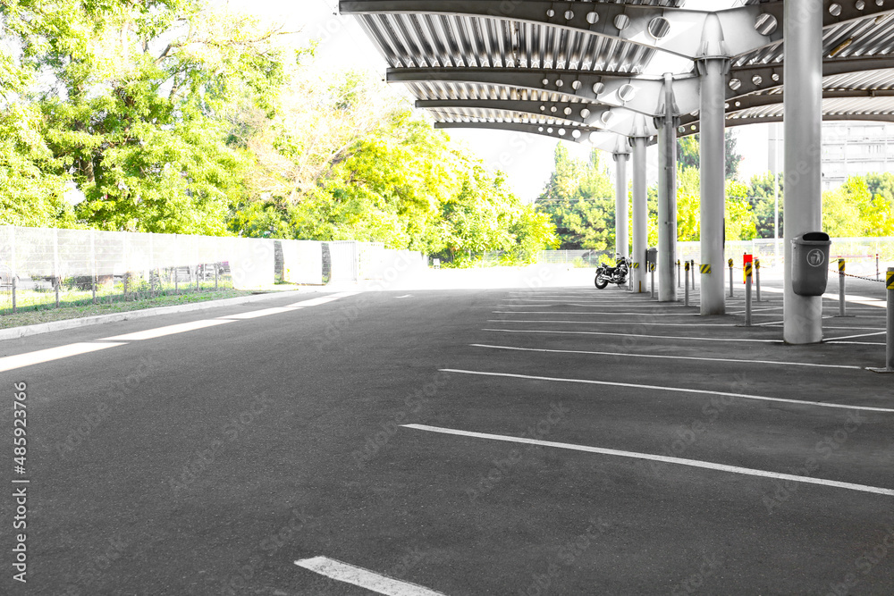 Empty car parking under canopy on green trees background