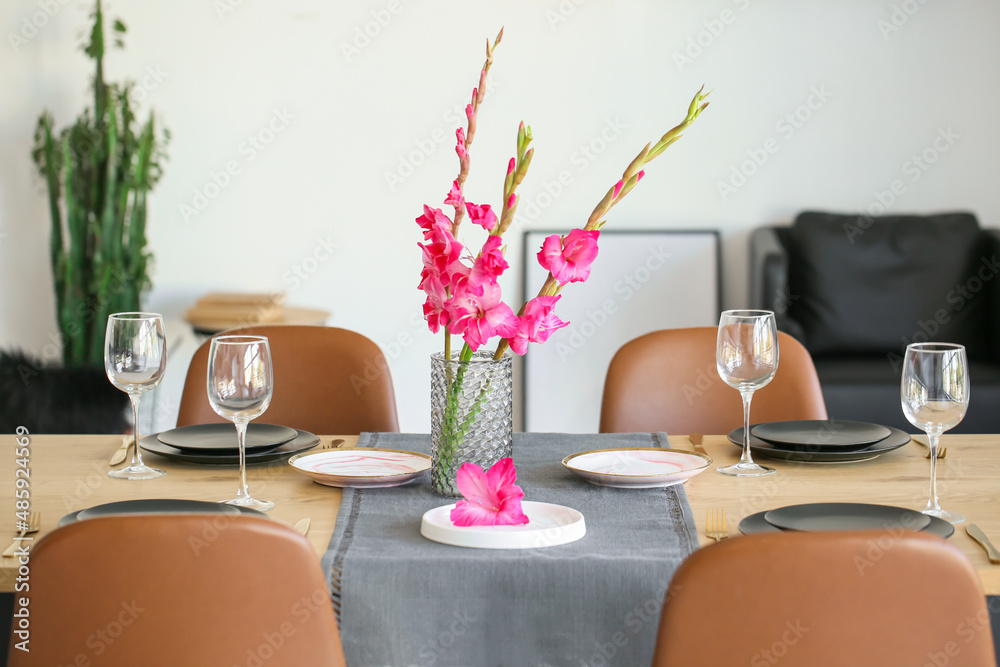 Stylish table setting and vase with beautiful Gladiolus flowers in dining room