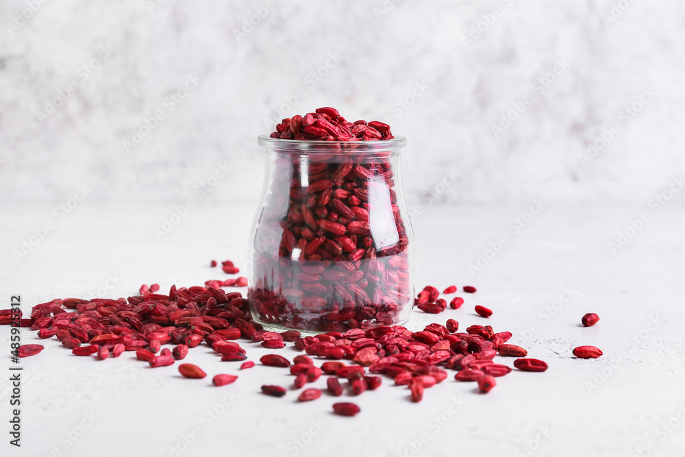 Jar with dried barberries on light background