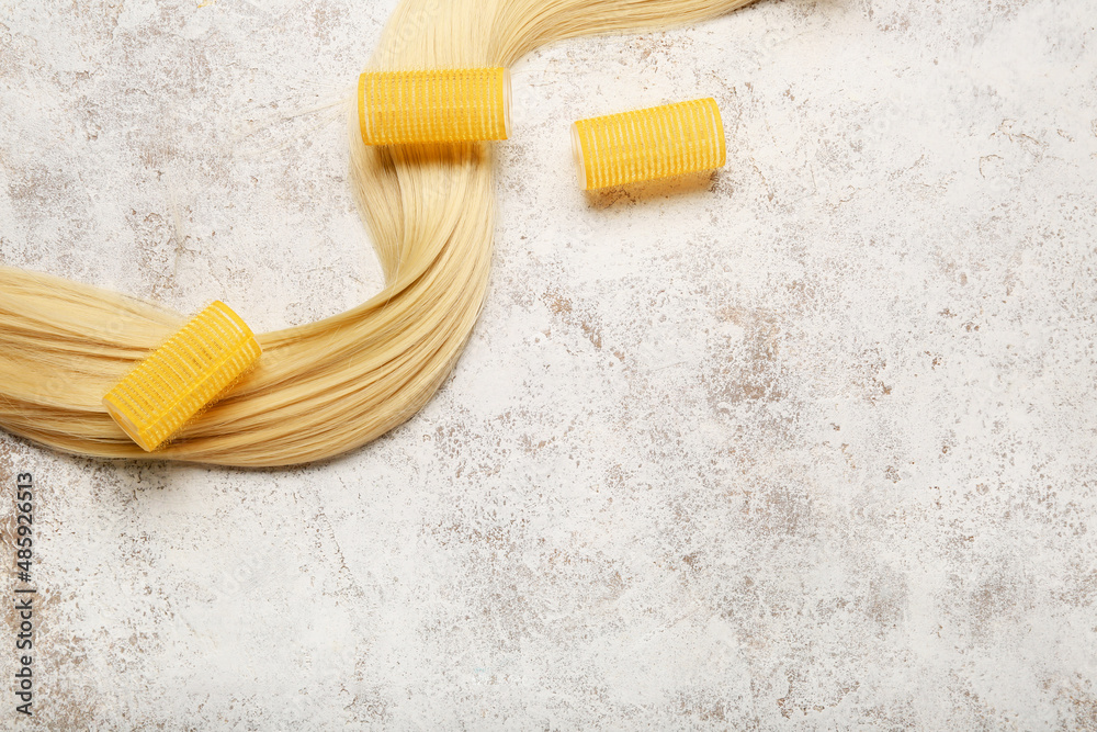 Long blonde hair with curlers on light background