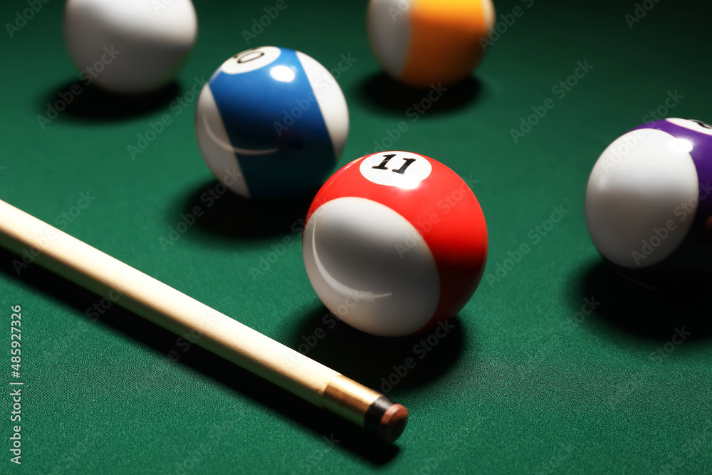 Different billiard balls with cue on green table