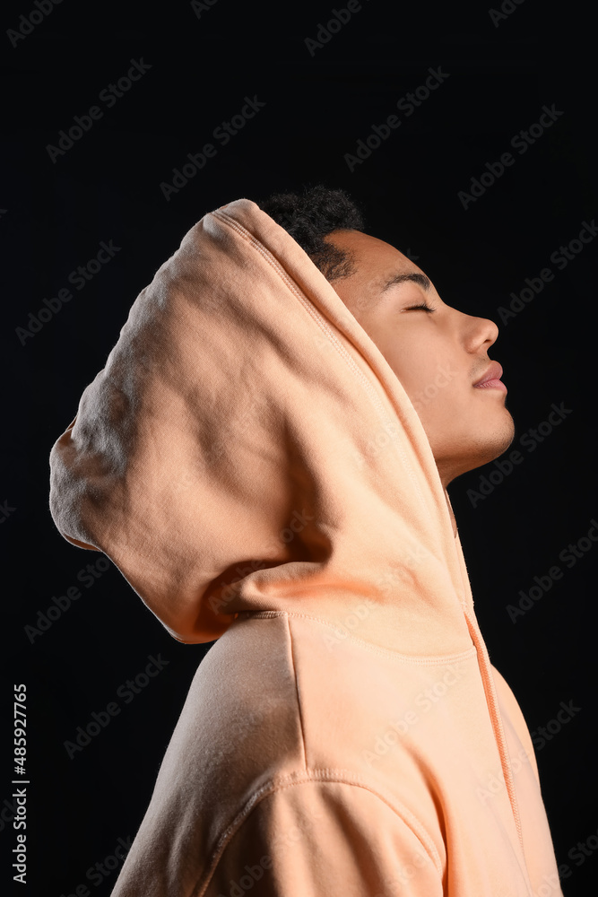 Peaceful African-American teenage boy in hoodie on black background