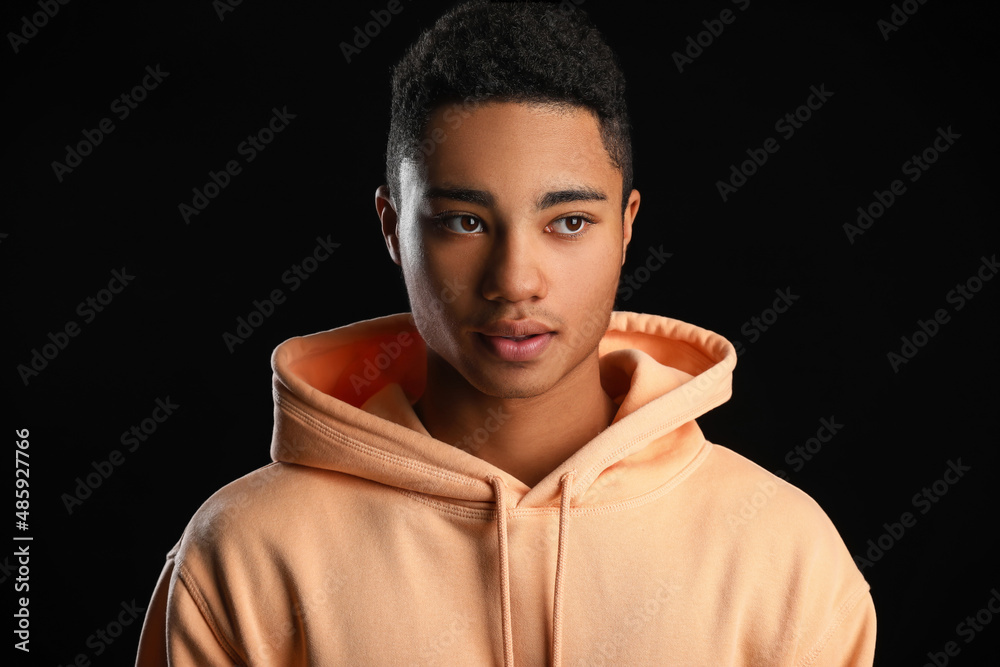 African-American teenage boy in hoodie on black background