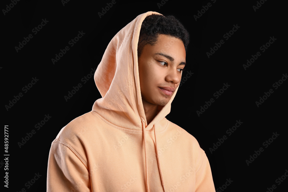 African-American teenage boy in hoodie on black background