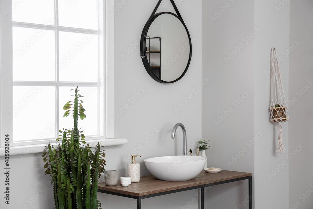 Table with sink and bath accessories near light wall in room