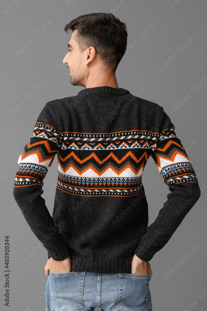 Handsome young man in knitted sweater on grey background, back view