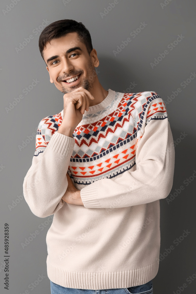 Handsome young man in knitted sweater on grey background