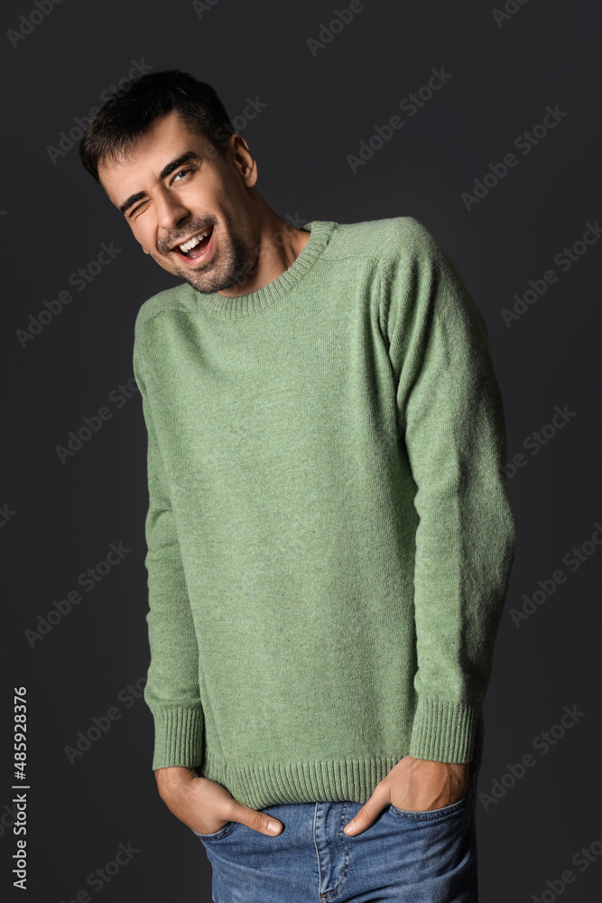 Handsome young man in knitted sweater on dark background