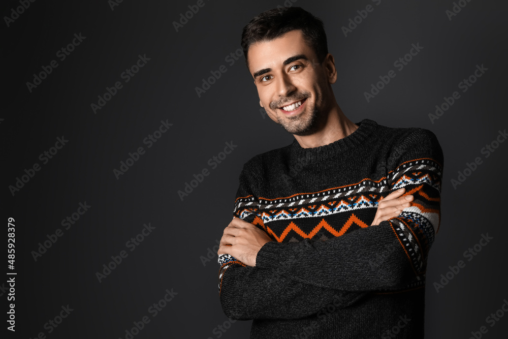 Handsome young man in knitted sweater on dark background