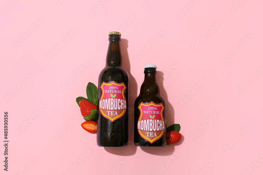 Bottles of tasty strawberry kombucha and mint on pink background