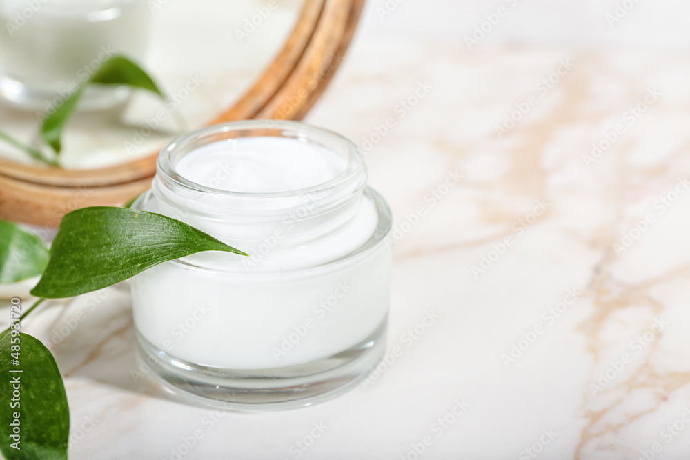 Jar with natural cosmetic cream and mirror on light background, closeup