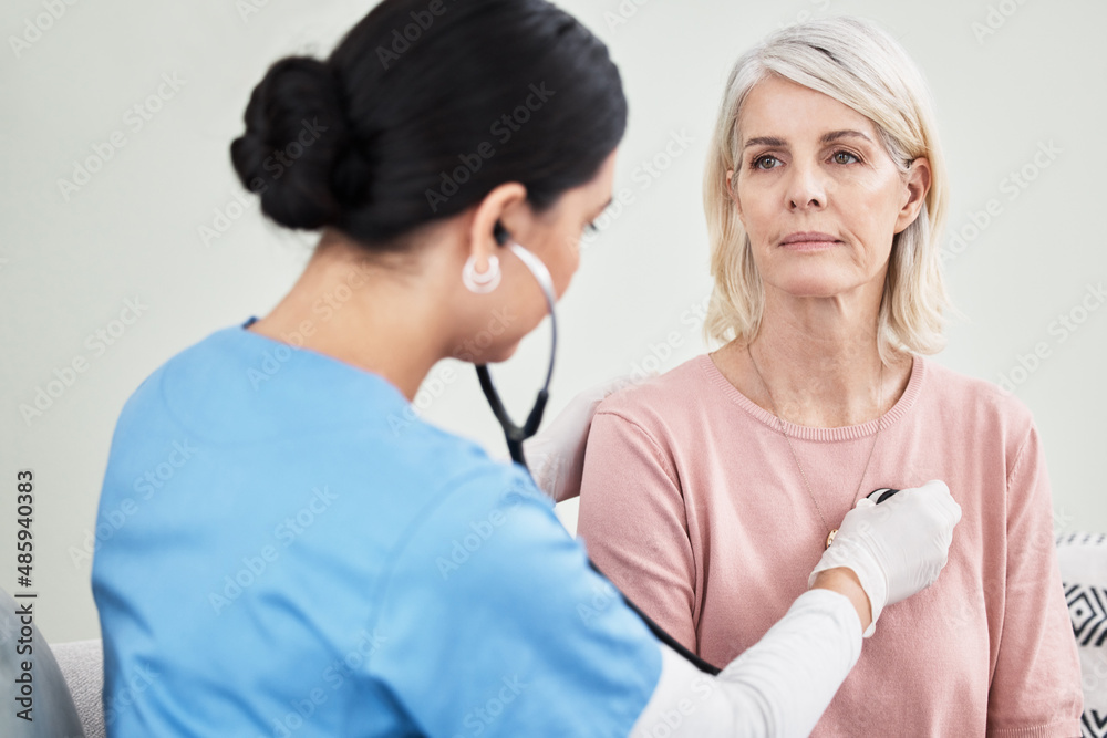 Let me take a listen. Shot of a female doctor examining a patient with a stethoscope.