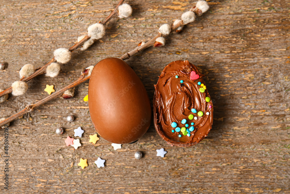 Easter egg with chocolate paste, sprinkles and pussy willow branches on wooden background