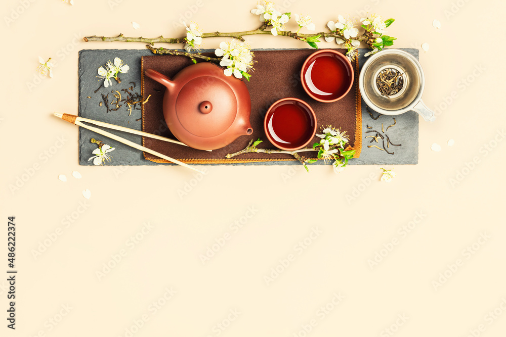 Asian Tea set on stone slate board, ceramic teapot, cups, dried tea and spring branches