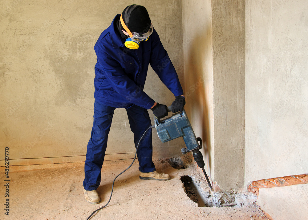 Worker with a jackhammer drilling concrete