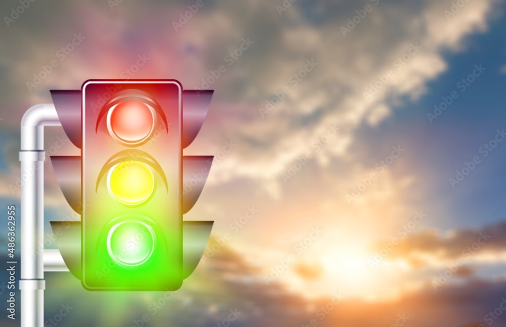 A traffic light on a blue sky with clouds, with all three lights on, green, orange and red.