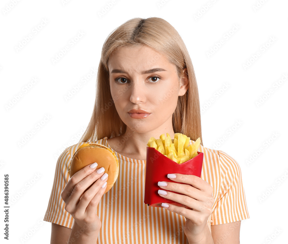 Stressed young woman with french fries and burger on white background