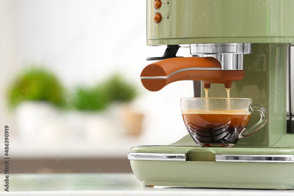 Preparing fresh espresso with coffee machine on table in kitchen