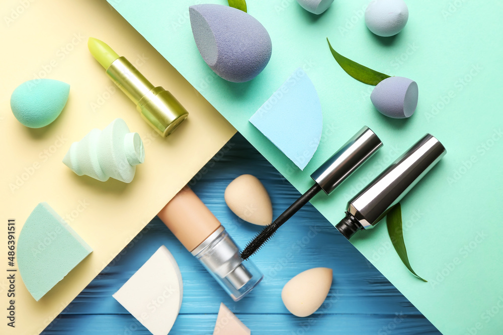 Composition with different makeup sponges and cosmetics on color background, closeup