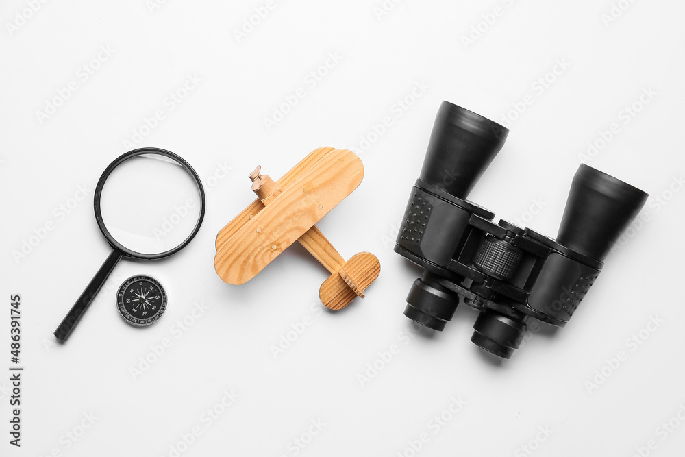 Binoculars, wooden plane, compass and magnifier on white background