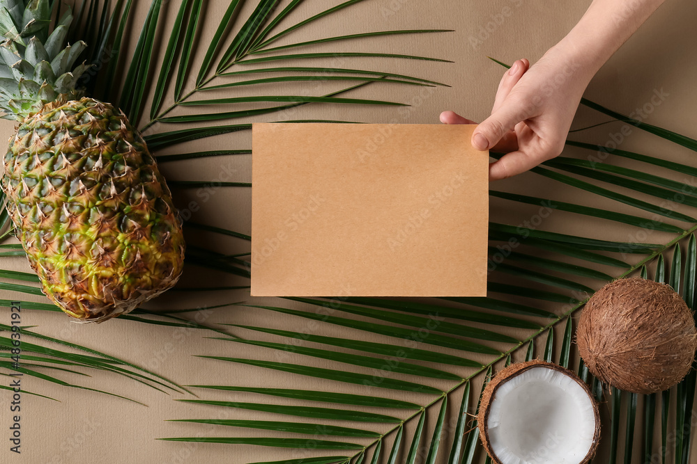 Female hand with blank card, fruits and palm leaves on color background