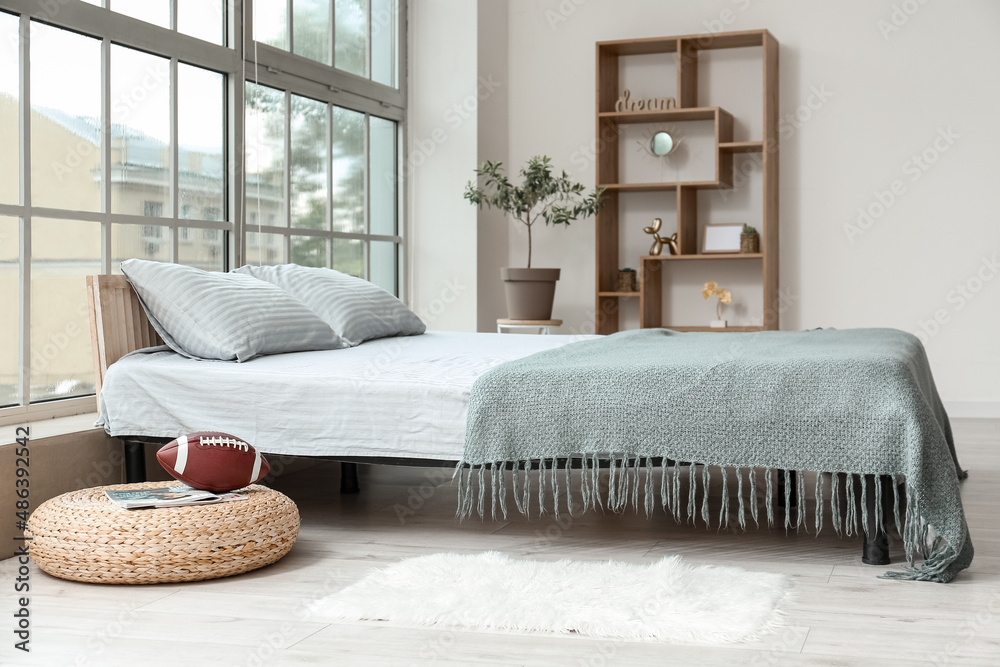 Modern bedroom interior with bed and bookshelf near window