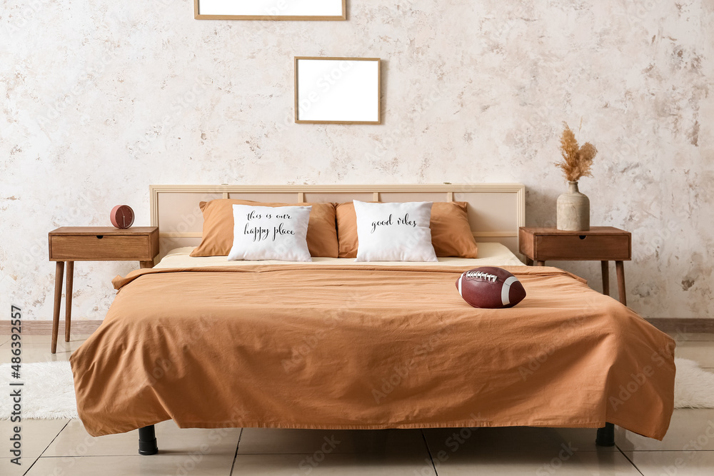 Rugby ball on bed in stylish bedroom interior