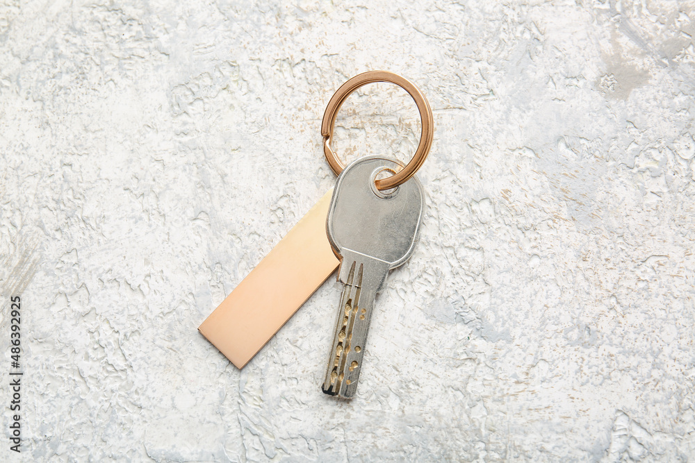 Key with stylish bronze keychain on light background