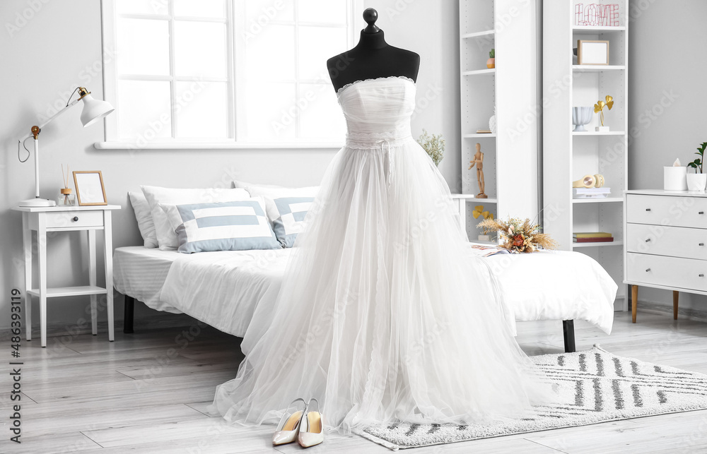 Mannequin with beautiful wedding dress prepared for ceremony in light room interior