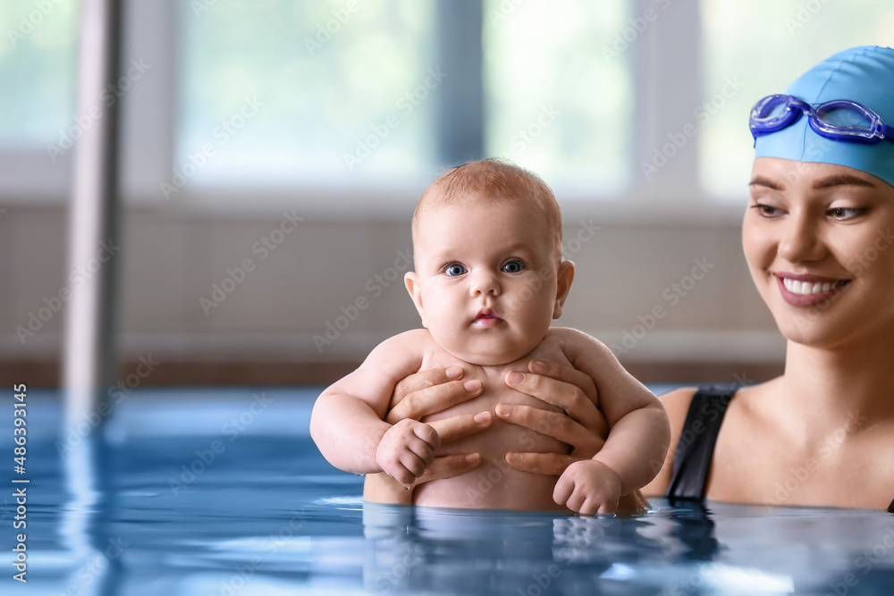 Young woman teaching little baby how to swim in pool