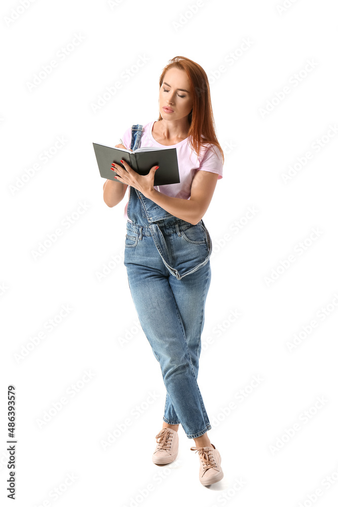 Young redhead woman writing in notebook on white background