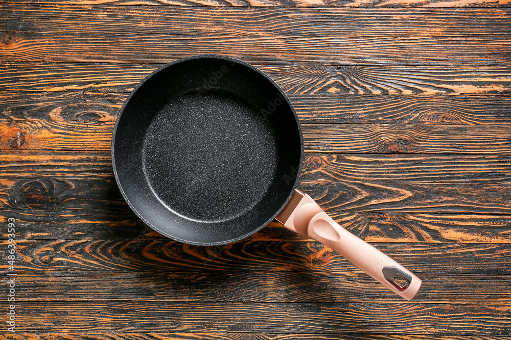 New frying pan on wooden background