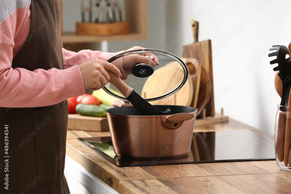 Woman cooking in copper pot at home, closeup