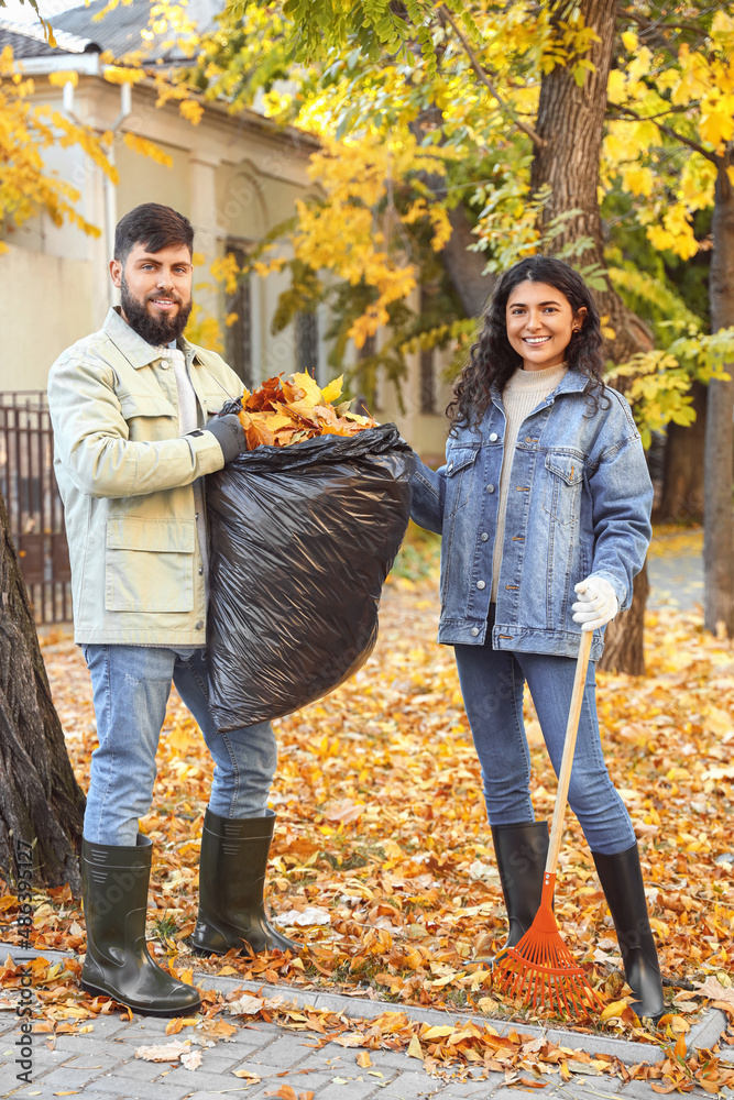 Couple gathering autumn leaves outdoors