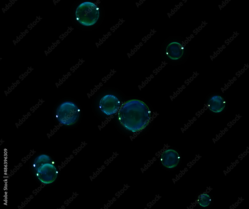 Many beautiful soap bubbles on dark background