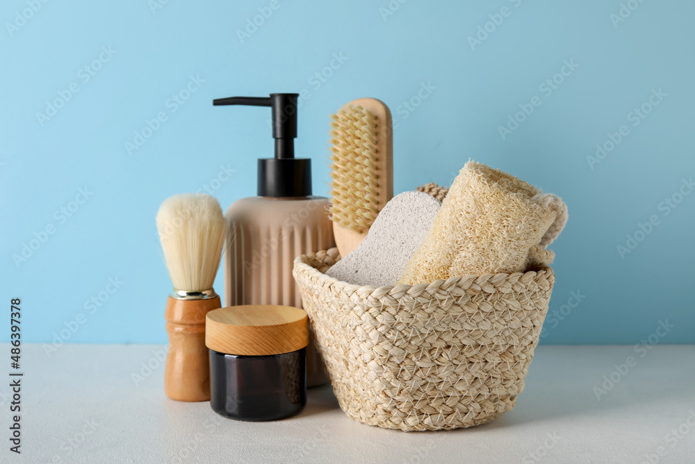 Set of bath supplies and cosmetics on table against color background