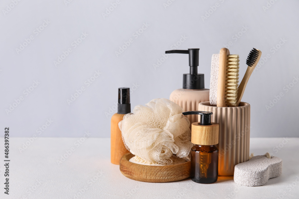 Different cosmetics and bath accessories on light background