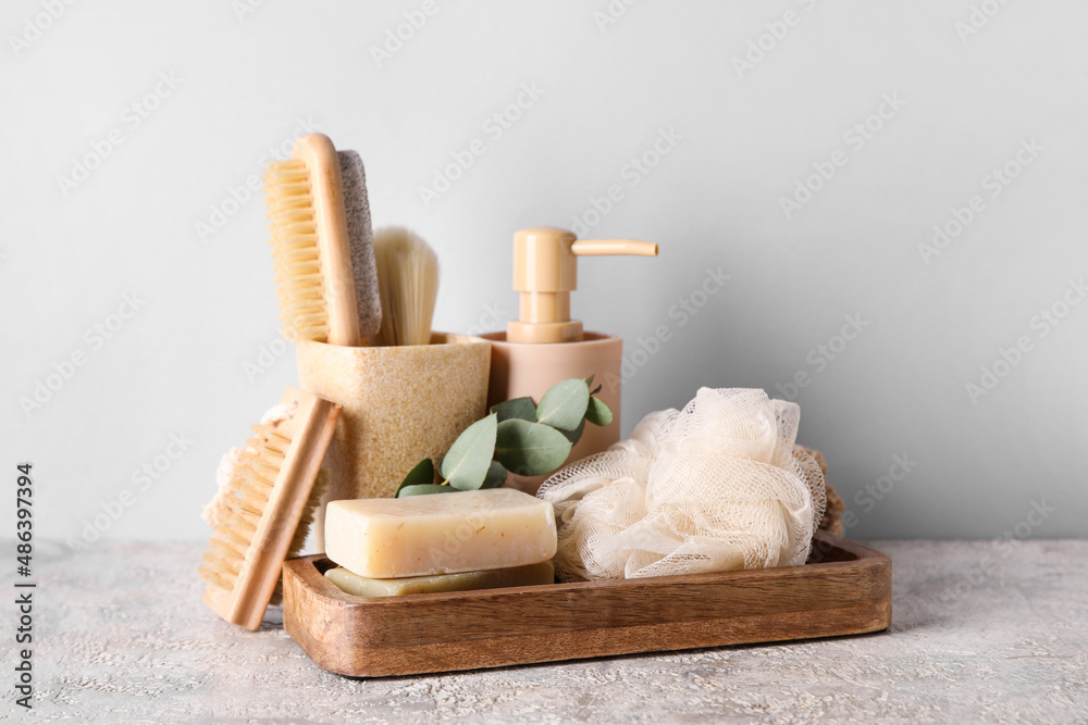 Different bath supplies with soap bars on light background