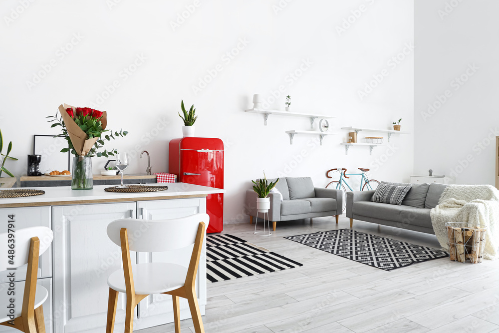 Interior of modern kitchen with counters, sofas and red fridge