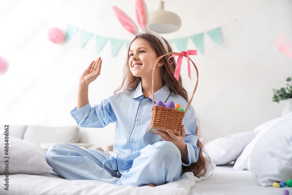 卧室里有兔子耳朵和复活节篮子的可爱小女孩