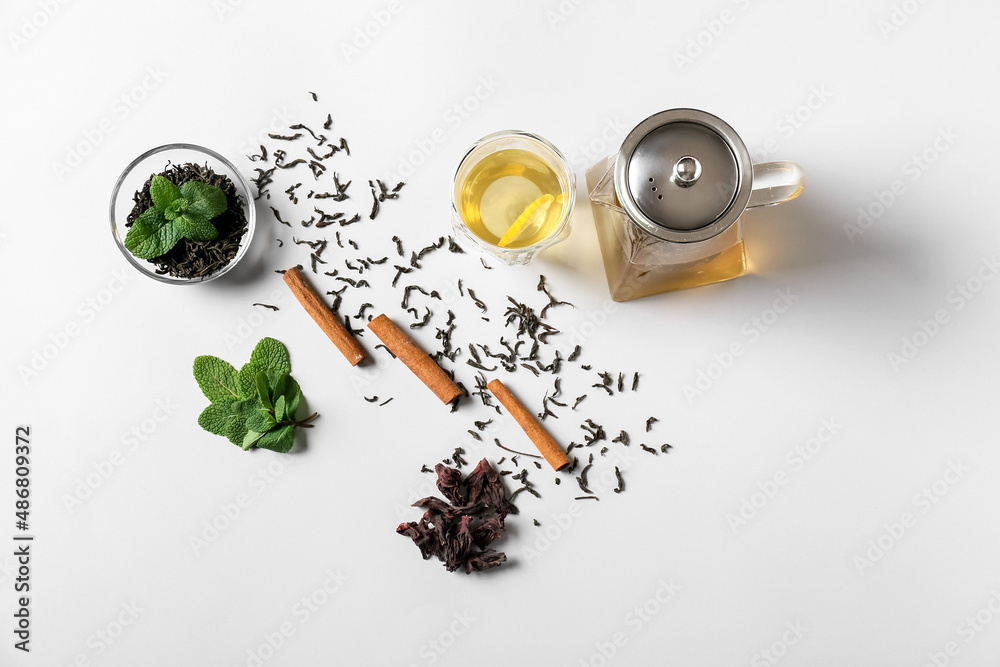 Composition of teapot and glass with tasty tea on light background