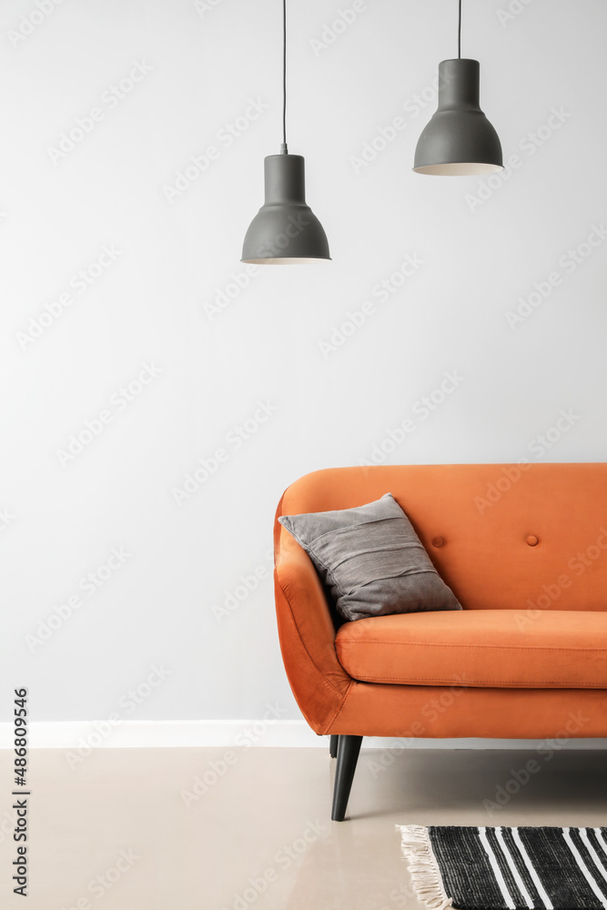 Stylish brown sofa with pillow and lamps near light wall