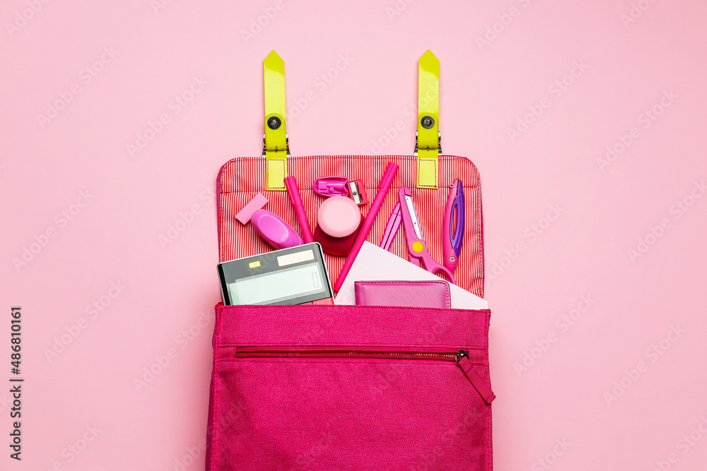 Stylish backpack with different stationery on pink background