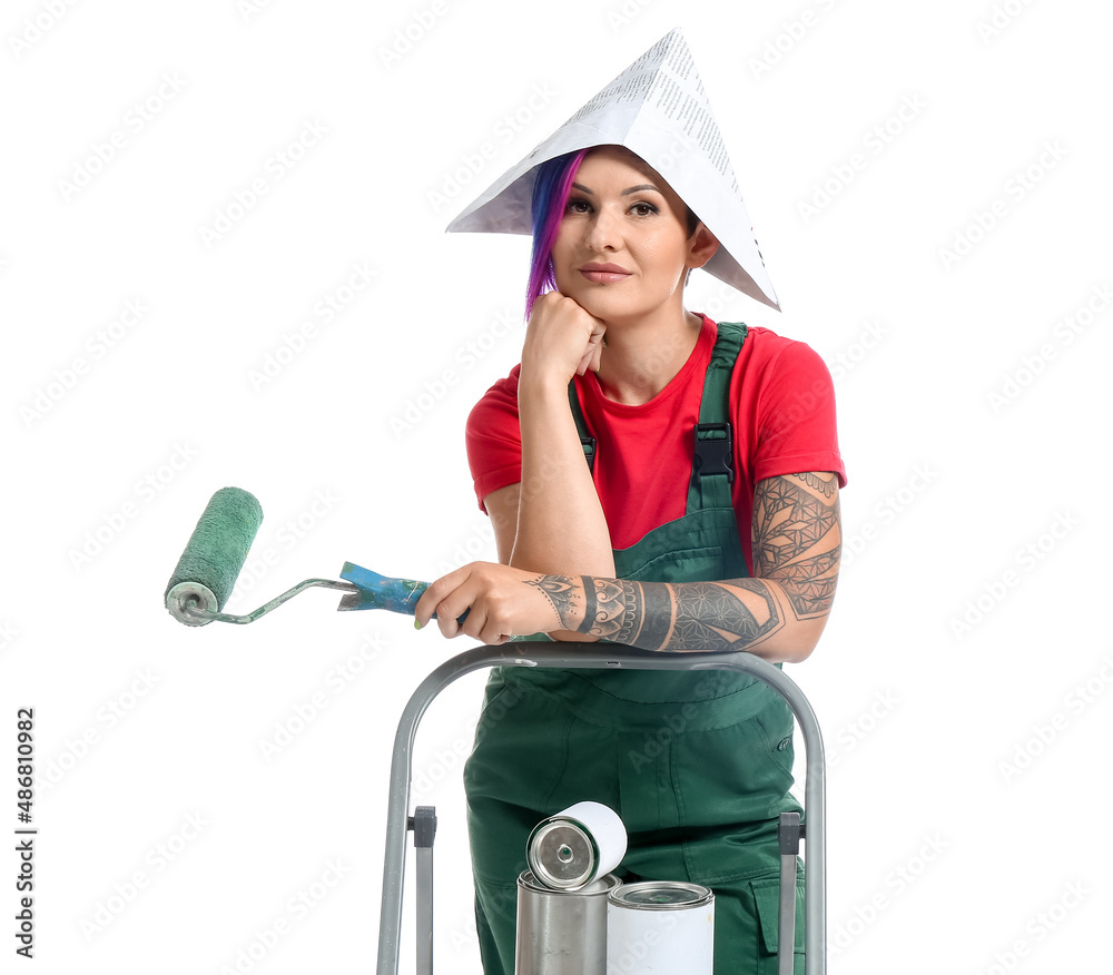 Female painter with paper hat, paint roller and ladder on white background